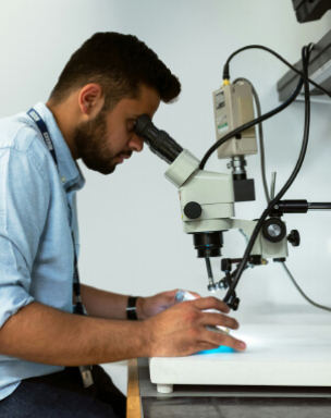 A person using a microscope in a laboratory setting.