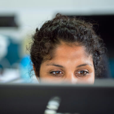 A close-up of a woman's face, focusing on her eyes as she looks at a computer screen.
