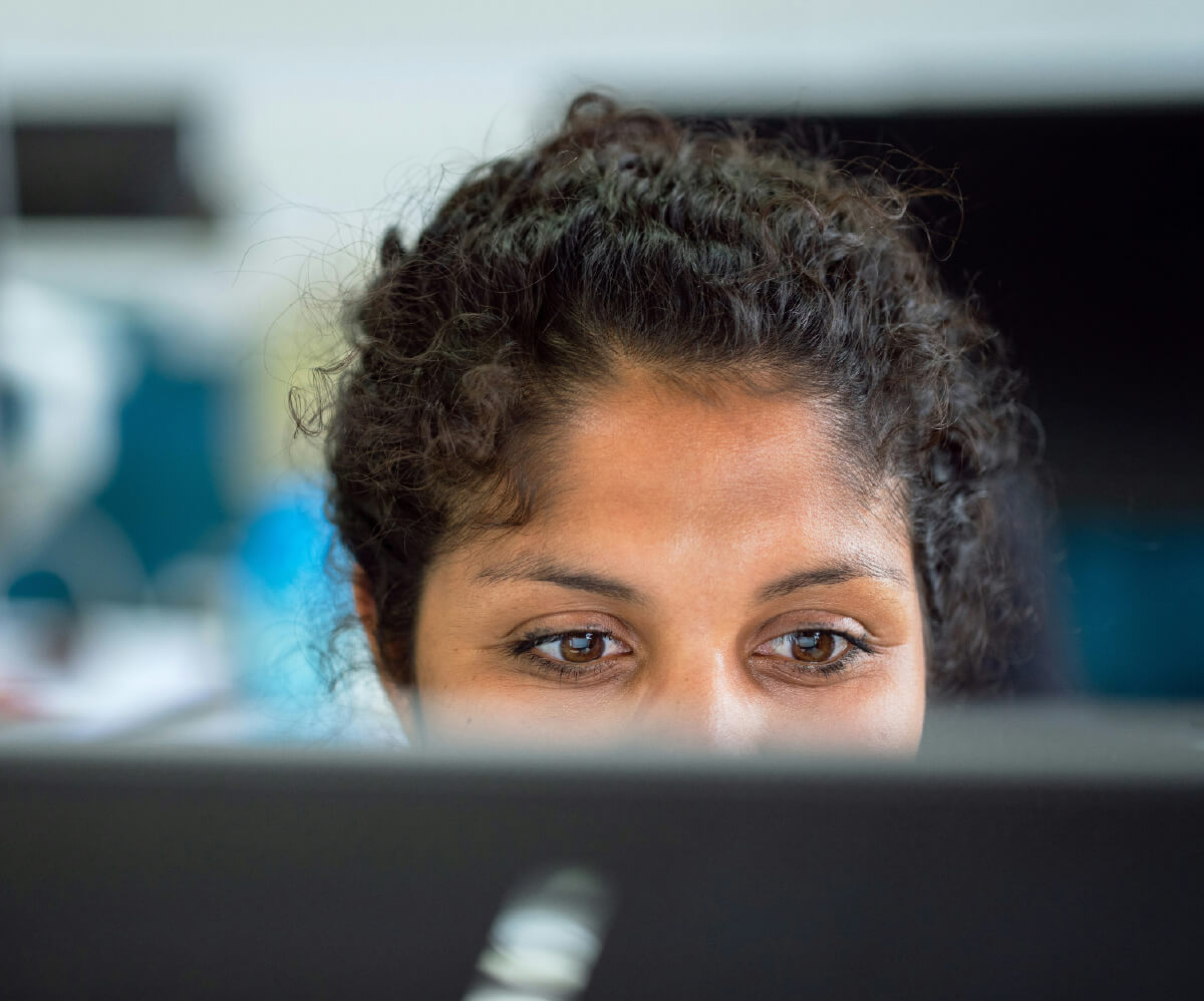 A close-up of a woman's face, focused on a computer screen.
