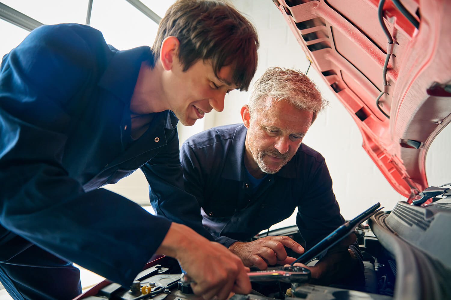 Image of two men examining a car engine.