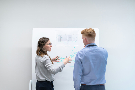Image of a man and woman working on a whiteboard.