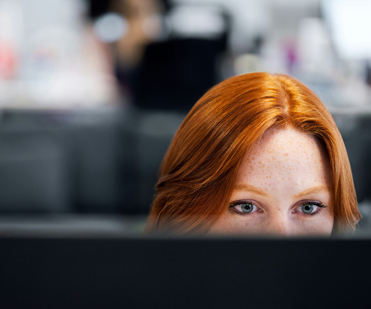 A close-up of a young woman, focusing intently on a computer screen.