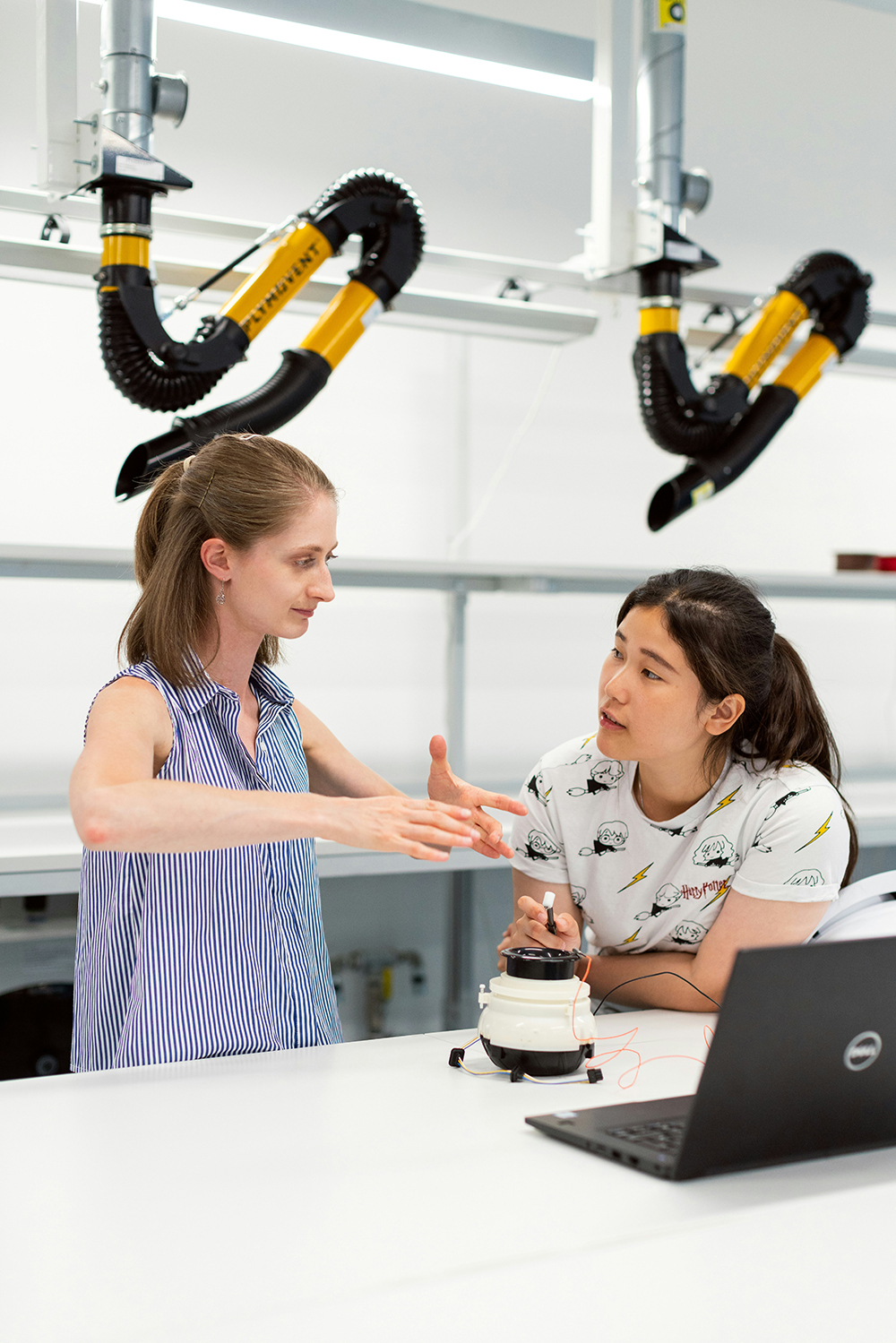 A teacher explains a concept to a student in a robotics workshop.